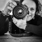 Sandra Kort met camera voor haar oog. Kleur consulente en fotograaf.