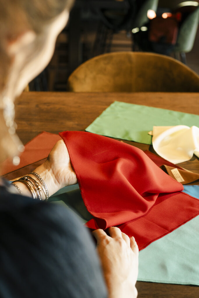 Personal branding shoot van kleurconsulent Rachel. Ze zit aan een tafel en heeft kleur doeken in haar hand.