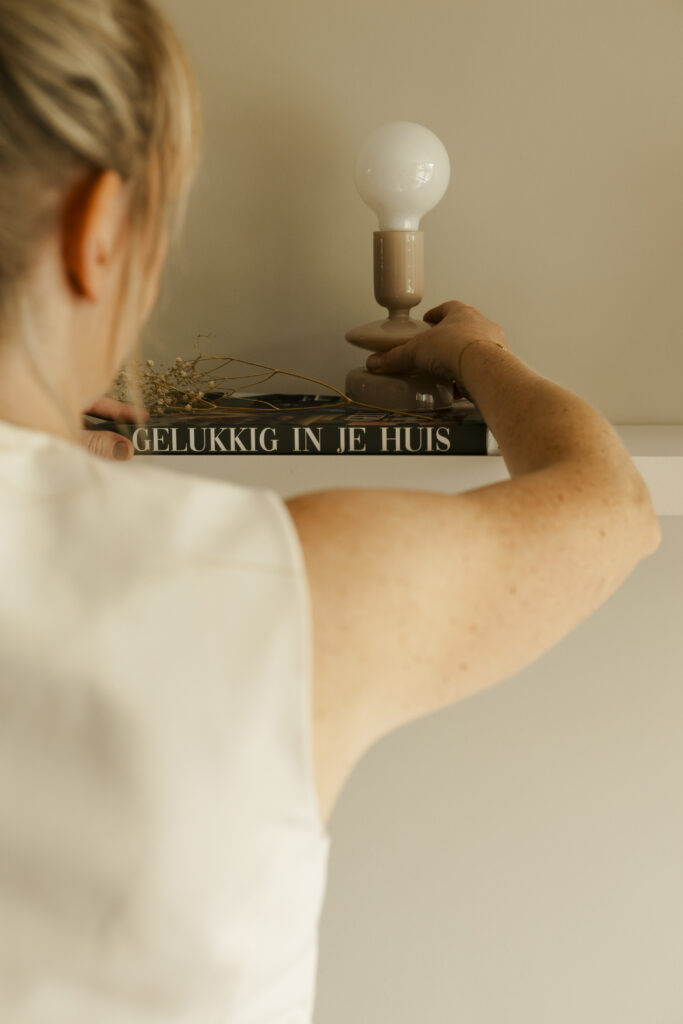 Personal branding shoot van interieurstyliste Marielle. Ze zet een lamp neer.